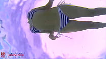 Slut in a striped bikini swimsuit. A bitch wriggles in the water like a snake, showing her ass.