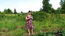 Milf without underwear under her dress outdoors in the yard. She picks a cucumber from the garden and fucks her cunt with it.