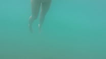 Nudist beach: Skinny dipped girl swimming in the sea.