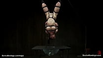 Bound tattooed redhead slave Tricia Oaks with big tits pressed between bars and chain run through crotch with bucket hung on the other side gets whipped then in inverted suspension ass hooked